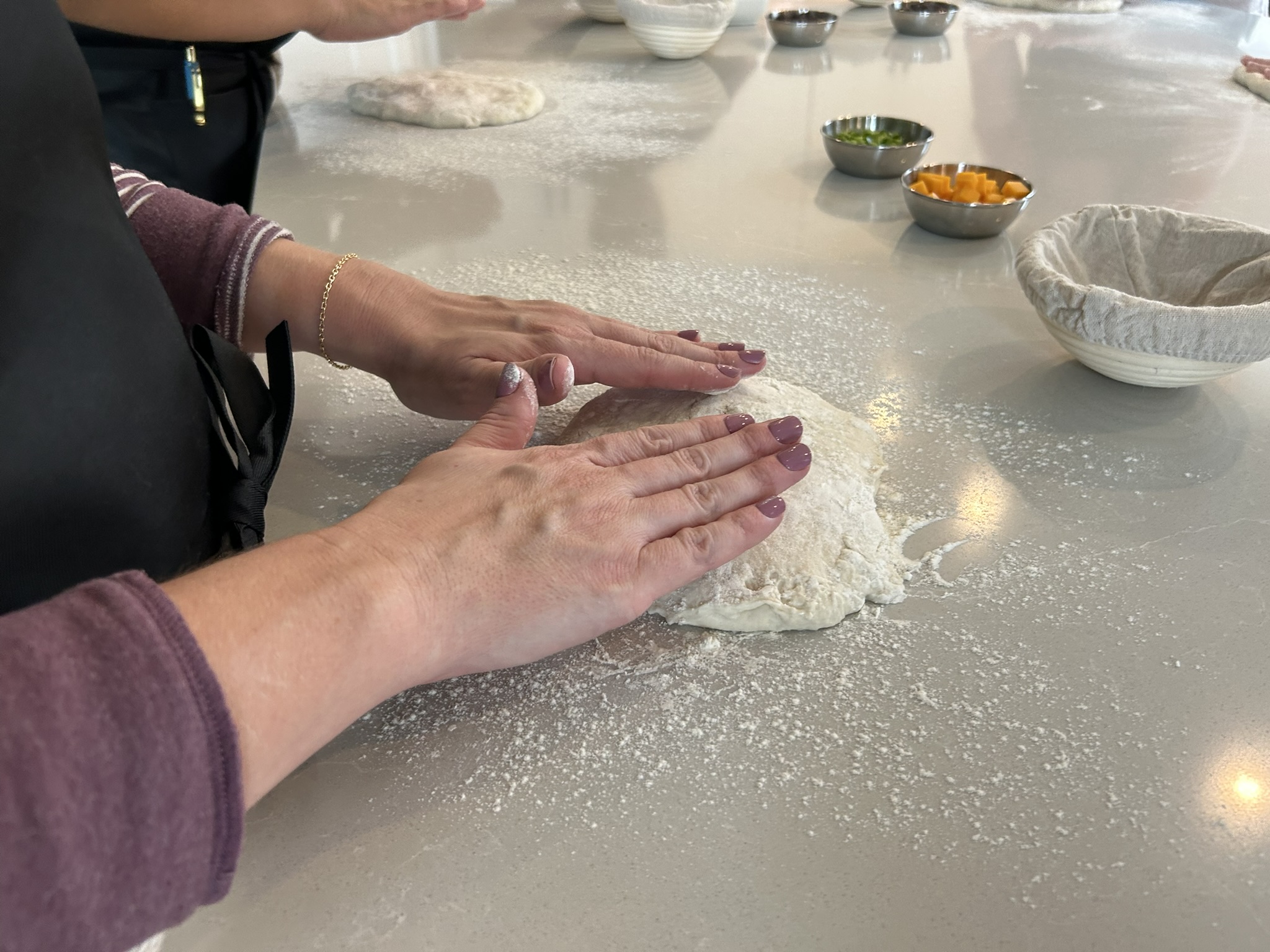Hands shaping sourdough dough on a floured counter