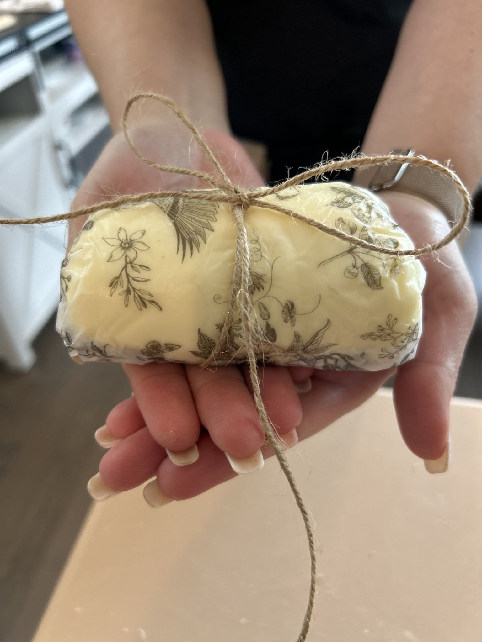 Finished butter log wrapped in floral paper, held in hands
