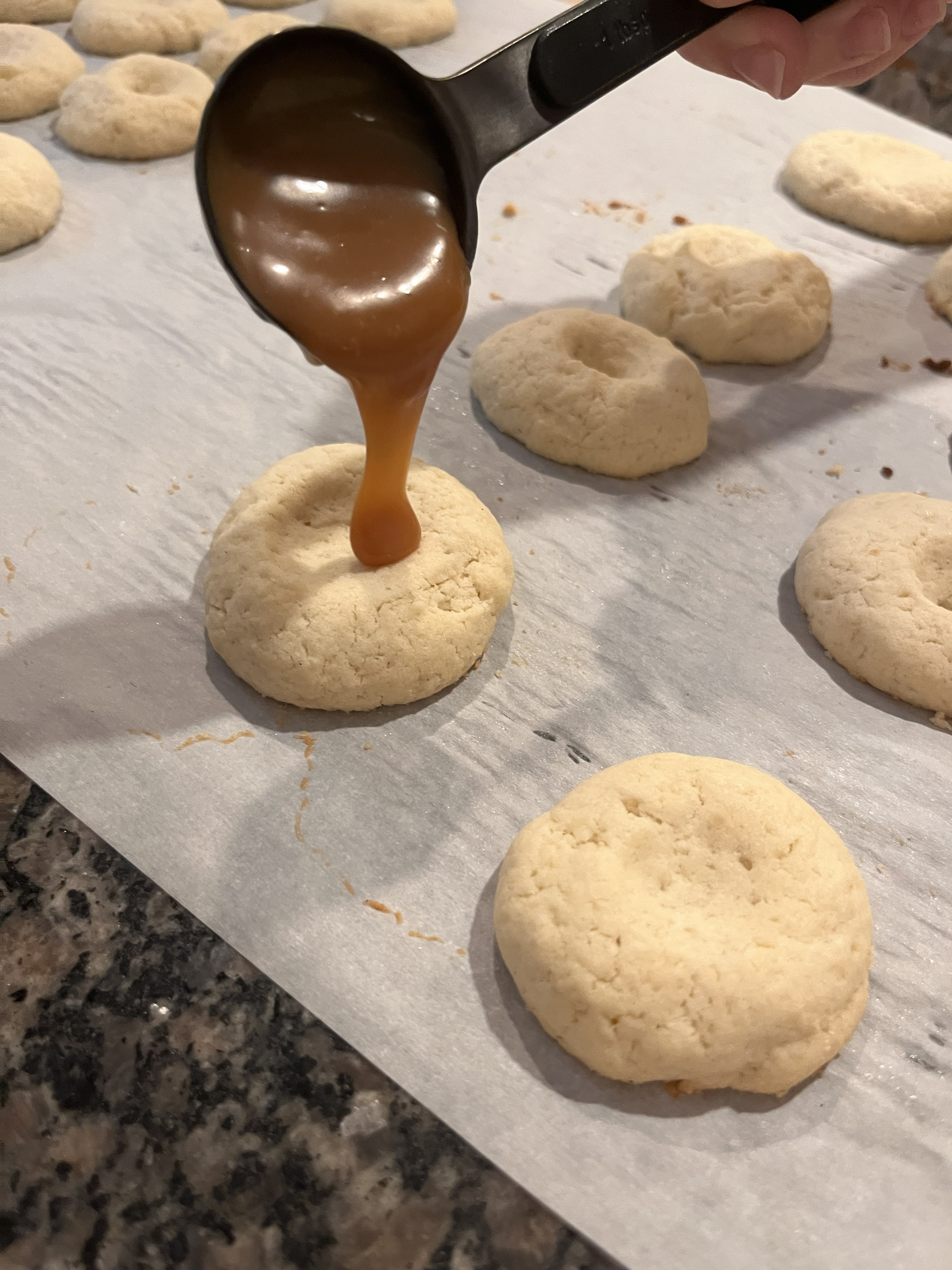 Homemade caramel being poured over a shortbread cookie